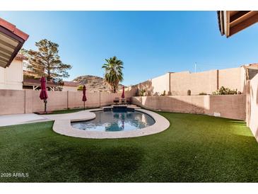 Backyard pool with artificial grass, decorative walls, and mountain views at 4346 E Corral St, Phoenix, AZ 85044