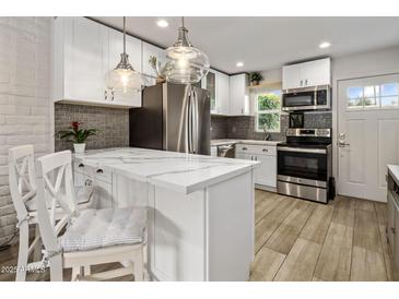 Modern kitchen features white cabinets, stainless steel appliances, and a stylish marble countertop island at 4800 N 68Th St # 225, Scottsdale, AZ 85251