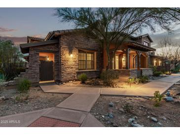 Charming stone home featuring a covered porch with wooden beams and professionally landscaped front yard at dusk at 17902 N 93Rd Way, Scottsdale, AZ 85255