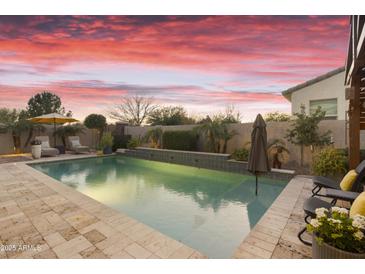 Inviting pool featuring a tanning ledge, mature landscaping, and an open patio with lounge chairs under a colorful sky at 20594 S 194Th Pl, Queen Creek, AZ 85142