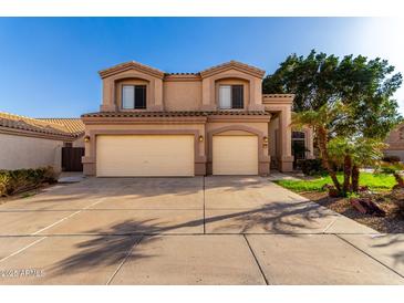 Inviting two-story home with a two-car garage, complemented by well-maintained landscaping and a clear blue sky at 13025 W Gelding Dr, El Mirage, AZ 85335