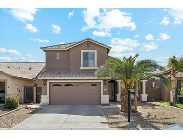 Two-story home showcasing a brown exterior, three-car garage, well-manicured lawn, and beautiful blue skies at 2755 E Cowboy Cove Trl, San Tan Valley, AZ 85143