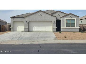 Charming single-story home featuring a gray stucco exterior, a two-car garage, and a well-maintained yard at 2994 N 305Th Dr, Buckeye, AZ 85396