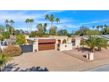 Charming exterior featuring a terra cotta roof, a large driveway, and a backdrop of mature palm trees at 4114 E Desert Cove Ave, Phoenix, AZ 85028