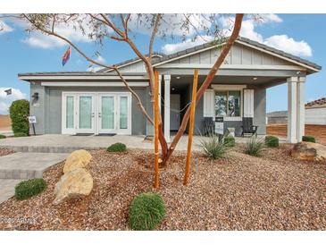 Charming single-story home with a covered porch and landscaped front yard featuring decorative rock and young trees at 22808 E Roundup Way, Queen Creek, AZ 85142