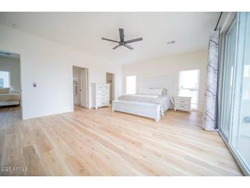 Bright main bedroom features a ceiling fan, light wood floors, and a sliding glass door at 2441 W Morten Ave, Phoenix, AZ 85021