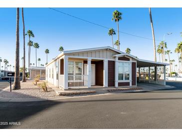 Charming single-story home with a covered porch, carport, and surrounded by lush palm trees at 2929 E Main St # 135, Mesa, AZ 85213