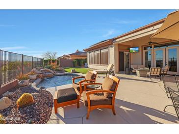 Inviting backyard featuring a pool with a waterfall, comfortable seating, and a covered patio with TV at 3109 W Summit Walk Ct, Anthem, AZ 85086