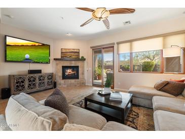 Bright living room features a fireplace, entertainment center, and sliding glass door to outdoor space at 11489 N 141St St, Scottsdale, AZ 85259