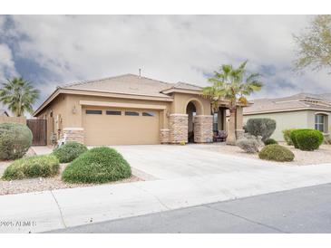 Inviting single-story home featuring a desert-style landscaped front yard, a two car garage, and stylish stone accents at 203 S La Amador Trl, Casa Grande, AZ 85194