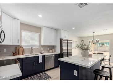 Well-designed kitchen featuring white cabinets, stainless steel appliances, and a large island with marble countertops at 25620 S Cloverland Dr, Sun Lakes, AZ 85248