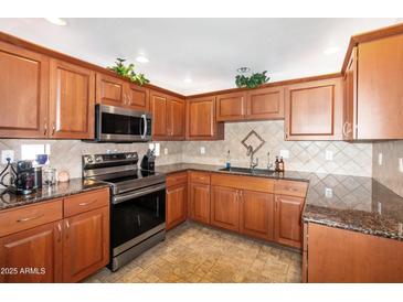 Well-lit kitchen featuring warm wood cabinetry, stainless steel appliances, and granite countertops at 9455 E Raintree Dr # 2032, Scottsdale, AZ 85260