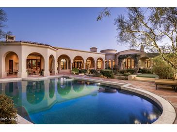 Beautiful swimming pool at dusk, surrounded by the well-lit home exterior and decorative landscaping at 9820 E Thompson Peak Pkwy # 841, Scottsdale, AZ 85255