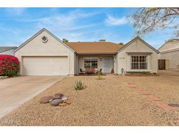 Charming single-story home featuring desert landscaping, a cozy front porch, and attached two-car garage at 1018 E Tonto Ln, Phoenix, AZ 85024