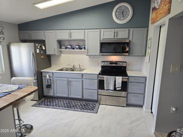 Well-lit kitchen features gray cabinetry, modern stainless steel appliances, and a stylish backsplash at 10624 W Oakmont Dr, Sun City, AZ 85351