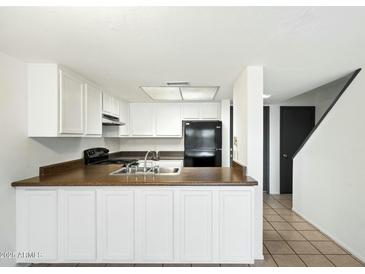 Bright kitchen features white cabinets, updated appliances, and dark countertops at 122 S Hardy Dr # 6, Tempe, AZ 85281