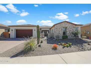 Beautiful single-story home featuring a stone exterior, desert landscaping, and a two-car garage at 18601 W Thunderhill Pl, Goodyear, AZ 85338