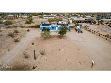 Aerial view of a blue single story house with a white door and a desert landscape with solar panels on the roof at 30446 W Portland St, Buckeye, AZ 85396