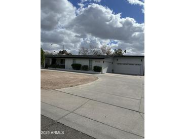 Charming single-story home featuring a spacious driveway, a two-car garage, and manicured landscaping under a partly cloudy sky at 5425 E Yale St, Phoenix, AZ 85008