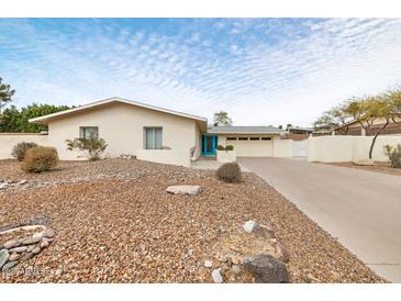 Charming single-story home featuring a bright blue door, desert landscaping, and an attached two-car garage at 7542 N 22Nd Pl, Phoenix, AZ 85020