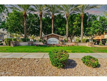 Landscaped community sign with manicured lawn and flowers, surrounded by mature trees and palm trees at 7769 W Bonitos Dr, Phoenix, AZ 85035