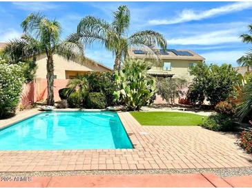 Inviting backyard pool surrounded by lush landscaping and brick pavers provides a relaxing outdoor oasis at 814 W Agrarian Hills Dr, San Tan Valley, AZ 85143