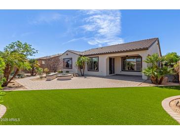 Spacious backyard featuring a patio, artificial grass, desert landscaping, and a built-in fire pit with seating at 4481 N Luna W Rd, Litchfield Park, AZ 85340