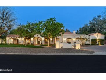 Elegant stucco home with tile roof, manicured lawn, and mature trees providing shade and curb appeal at 8325 N 73Rd Pl, Scottsdale, AZ 85258