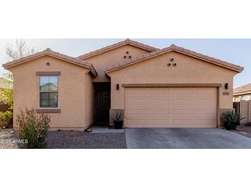 Charming single-story home with a tan exterior, a two-car garage, and simple desert landscaping at 18842 N Lariat Rd, Maricopa, AZ 85138