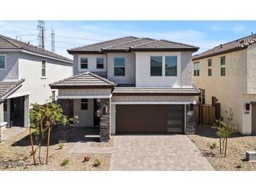 Charming two-story home featuring stone accents and a modern brown garage door, complemented by desert landscaping at 7988 W Griswold Rd, Peoria, AZ 85345