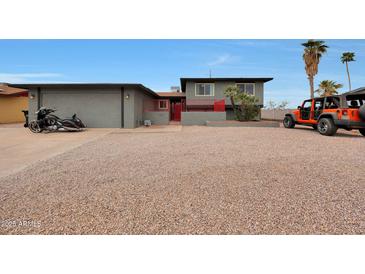 Two-story home with gravel landscaping, black motorcycle and orange Jeep out front at 11652 N 49Th Dr, Glendale, AZ 85304