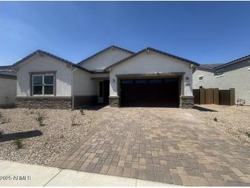 Charming single-story home featuring a brick-paved driveway and neutral-toned stucco exterior at 15822 W Bronco Trl, Surprise, AZ 85387