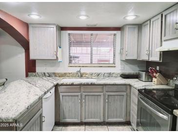 Well-lit kitchen featuring granite countertops and modern stainless steel appliances at 17648 N 36Th St, Phoenix, AZ 85032