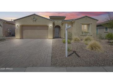Inviting exterior view of a tan home featuring a paver driveway and desert landscaping at 32366 N 133Rd Ln, Peoria, AZ 85383
