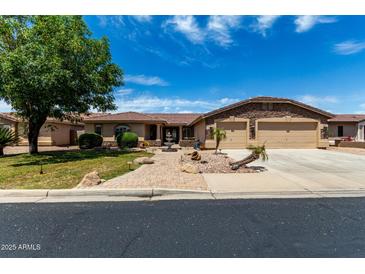 Charming single-story home with a well-manicured lawn, mature tree, and a spacious three-car garage at 13516 W Windsor Blvd, Litchfield Park, AZ 85340