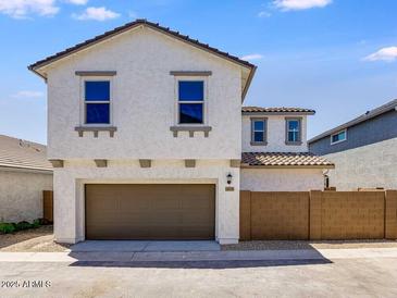 Two-story home featuring a two-car garage, a brown-tiled roof, and a light-colored stucco exterior at 14636 W Sand Hills Rd, Surprise, AZ 85387
