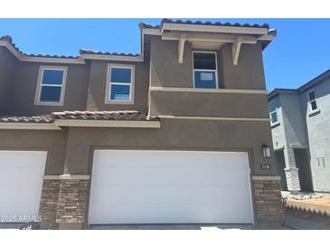 Modern two-story home with a two-car garage, stone accents, and a red tile roof against a clear blue sky at 21130 N 58Th St, Phoenix, AZ 85054