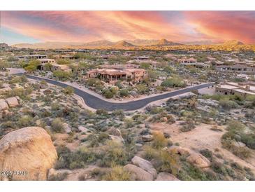 Expansive aerial view of desert homes surrounded by natural rock formations and mountains under colorful sunset skies at 10671 E Hedgehog Pl, Scottsdale, AZ 85262