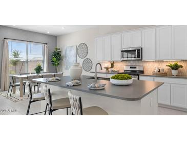 Bright kitchen features a large island, modern appliances, and an adjacent dining area at 15362 W Cottontail Ln, Surprise, AZ 85387
