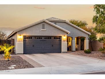 Charming single-story home with a gray garage door and well-maintained front yard, illuminated by exterior lights at 2108 E Lindrick Dr, Gilbert, AZ 85298