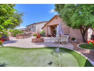 Landscaped backyard with a fire pit, outdoor kitchen, and putting green at 21998 N Greenland Park Dr, Maricopa, AZ 85139