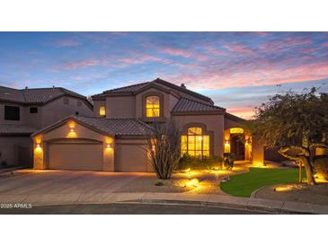 Inviting home with manicured landscaping, three-car garage, and warm exterior lighting at sunset at 4235 W Harrison St, Chandler, AZ 85226