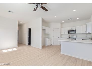 Open-concept living room and kitchen boasts wood-look floors, modern appliances, and white cabinets at 463 W Taylor Ave, Coolidge, AZ 85128