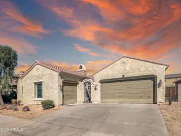 Charming stucco home featuring a three-car garage, desert landscaping, and a barrel tile roof under a colorful sunset sky at 17346 W Lincoln St, Goodyear, AZ 85338