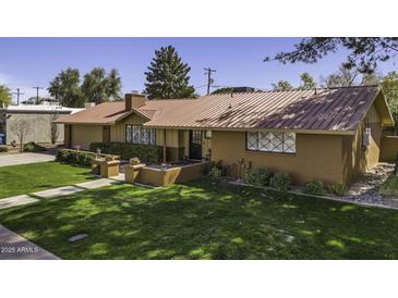 Charming single-story home with a metal roof, manicured lawn, and mature trees at 325 E Aepli Dr, Tempe, AZ 85282