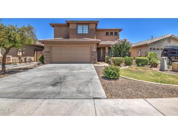 Charming two-story home features a two-car garage, desert landscaping and a concrete driveway at 45338 W Norris Rd, Maricopa, AZ 85139