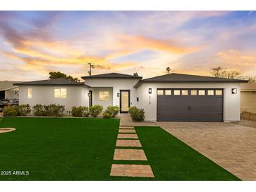 Charming home with a green lawn and a brick walkway leading to the front door with garage at right at 6719 N 10Th Pl, Phoenix, AZ 85014