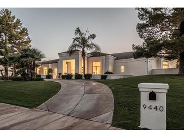 Elegant single-story home featuring a well-manicured lawn and a circular driveway leading up to the entrance at 9440 N 57Th St, Paradise Valley, AZ 85253