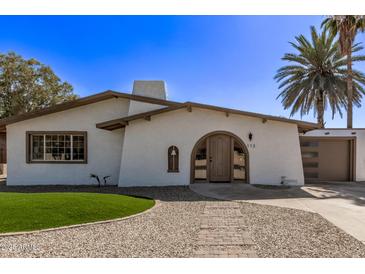 Charming home featuring an arched entryway, low-maintenance landscaping, and a tan stucco exterior with a detached garage at 113 W Rawhide Ave, Gilbert, AZ 85233