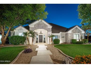 Charming home with stone accents, lush landscaping, and a welcoming walkway, enhanced by elegant outdoor lighting at 23420 S 202Nd St, Queen Creek, AZ 85142